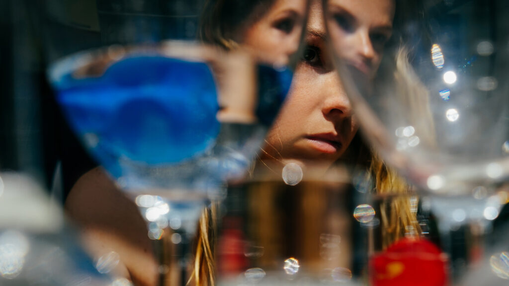 Woman's face obscured by drinks.
